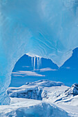 Blick unter einen blauen Eisbogen eines Eisbergs.