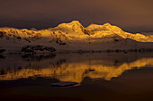 Golden light on mountainous coast, and reflections in the strait.