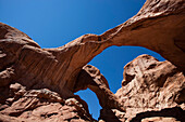 Ein Mann steht unterhalb des Double Arch im Arches National Park.