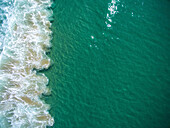 Turquoise blue water breaks against the sand on Zuma beach.