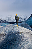 Ein Mann geht zwischen einer der vielen Gletscherspalten auf dem Vatnajokull-Gletscher hindurch.