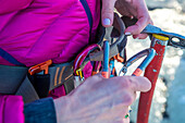 A woman attaches herself to a safety line with an ice axe in hand.
