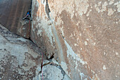 Ein Bergsteiger arbeitet sich an einer technischen Granitwand hoch.