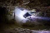 Ein Höhlentaucher geht durch einen verschlammten Gang.