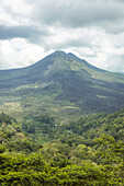 Overview of Mount Batur (Kintamani Volcano) in South Batur with a cloudy sky and lush vegetation; Kintamani, Bangli Regency, Bali, Indonesia