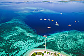 Aerial view of boats moored offshore of an island in Komodo National Park with a dock extending into the surrounding turquoise water; East Nusa Tenggara, Lesser Sunda Islands, Indonesia