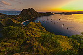 Boats moored in the bay at Padar Island in Komodo National Park in the Komodo Archipelago with the golden glow of sunset; East Nusa Tenggara, Indonesia