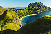 Boats moored in the bay at Padar Island in Komodo National Park in the Komodo Archipelago with sunlit grassy slopes and a blue sky; East Nusa Tenggara, Indonesia