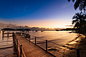 Blick auf die Bucht von Samana von einem Dock aus bei Sonnenuntergang mit Booten, die im Hafen entlang der Küste von Samana vertäut sind; Halbinsel Samana, Dominikanische Republik, Karibik