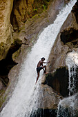 Ein Mann erklimmt den Wasserfall im Basin Bleu.