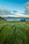 Dibidil Bothy in der Abenddämmerung mit der Isle of Eigg im Hintergrund, Rum; Schottland, Vereinigtes Königreich