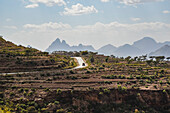 Ländliche Szene mit terrassiertem Ackerland und einem Lastwagen, der eine Bergstraße im äthiopischen Hochland entlangfährt; Äthiopien