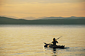A woman kayaking on Sebago Lake.; Sebago Lake, Maine.
