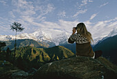 Frau mit Fernglas in der Nähe der Annapurna Range, Nepal; Annapurna Range, Nepal.