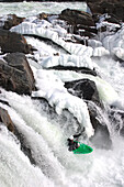 Wildwasserkajakfahrer fährt im Winter über einen fast gefrorenen Wasserfall; Great Falls, Potomac River, Maryland.