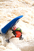 Kayaker flips upside down as he paddles through raging rapids.; Potomac River - Maryland/Virginia, USA