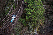 Touristen unter Regenschirmen blicken von einer Hängebrücke auf das japanische Iya-Tal, ein abgelegenes Gebirgstal im Westen der Präfektur Tokushima auf der Insel Shikoku; Iya-Tal, Präfektur Tokushima, Japan