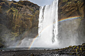 Kaskadenförmiger Wasserfall und Regenbogen; Island