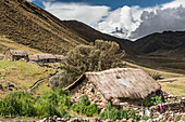 Bauerngemeinschaft im Lares-Tal mit den Anden, die sich über den Steinhäusern mit Strohdächern abzeichnen; Lares-Tal, Cusco, Peru