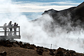 Menschen stehen auf der Aussichtsplattform und fotografieren den Myvatn-See, umgeben von dem Dampf, der aus den geothermischen Schloten aufsteigt. Das Myvatn-Seegebiet ist eine der geologisch aktivsten Regionen Islands; Myvatn-See, Nordisland, Island