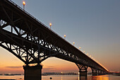 Silhouette der Jangtse-Brücke, die den Fluss Jangtse überquert, beleuchtet in der Dämmerung; Nanjing, Provinz Jiangsu, China