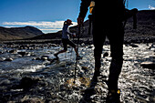 Teammitglieder einer Klimawandel-Expedition in Grönland wandern und überqueren einen Fluss, um ins Grottedalen zu gelangen und das Höhlental zu erkunden; Grönland