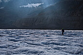 An expedition leader walking across the Aletsch Glacier in search of moulins and unexplored glacier caves.