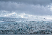 Views of the blue ice of the Fjallsjokull Glacier terminus stands out against the grey, misty clouds, taken from the Fjallsarlon Glacier Lagoon at the south end of the famous Icelandic glacier Vatnajökull in Southern Iceland; South Iceland, Iceland