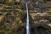 Nahaufnahme eines stürzenden Wasserfalls gegen die felsigen Klippen im Wanderparadies der Mulagljufur-Schlucht; Südisland, Island