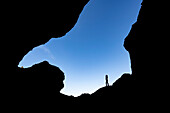 Silhouette einer Frau vor blauem Himmel, die die Schluchten und die Landschaft von Thorsmork erkundet, einem Gebiet von außergewöhnlicher Schönheit in Südisland; Thorsmork, Südküste, Island