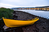Moored rowing skiff in vibrant yellow on the shore at the water's edge near the town of Cheticamp; Cabot Trail, Cape Breton Island, Nova Scotia, Canada