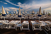 Strand mit Reihen von Stühlen und Sonnenschirmen in Blau und Weiß in Nizza, Frankreich; Nizza, Côte d'Azur, Frankreich
