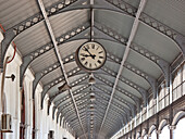 Clock hanging from the rafters of a ceiling; Maputo, Mozambique