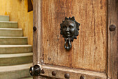 A Door Knocker With The Image Of A Human Face On A Wooden Door; Sayulita Mexico