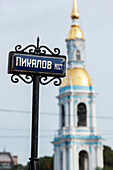 Ein Straßenschild mit der Schiffskathedrale St. Nikolaus im Hintergrund; St. Petersburg Russland