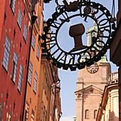Sign On The Side Of A Building With A Clock Tower In The Background; Stockholm Sweden