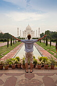 Ein junger Mann mit ausgestreckten Armen, der das Tah Mahal betrachtet; Agra Uttar Pradesh Indien