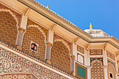 Ein junges Paar schaut aus einem kleinen Fenster im Amer Fort; Jaipur Rajasthan Indien