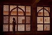 Ein junger Mann steht vor einem verschnörkelten Fenster; Jaipur Rajasthan Indien