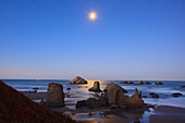 Monduntergang über Felsformationen, die sich bei Ebbe in den Gezeitentümpeln spiegeln, Bandon Beach; Oregon, Vereinigte Staaten Von Amerika