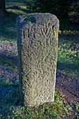Ein alter Steinmarker mit abgenutzter Inschrift; Derbyshire, England