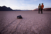 Paar steht in der Nähe von sich bewegenden Felsen an der Racetrack Playa; Death Valley Kalifornien Vereinigte Staaten Von Amerika