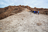 Eine Gruppe von Menschen, die einen Pfad bei der antiken Festung Masada hinaufgehen; Israel