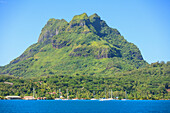 A Large Rock Formation Against A Blue Sky Along The Coast; Bora Bora Society Islands French Polynesia South Pacific