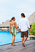 A Couple Walks Along A Boardwalk In The Bora Bora Nui Resort & Spa; Bora Bora Island Society Islands French Polynesia South Pacific