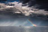 Ein Regenbogen durch Sturmwolken über einem Meer mit zwei Schiffen; Whitley Bay Northumberland England