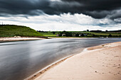 Sandstrand entlang eines Flusses mit Sturmwolken; Alnmouth Northumberland England