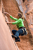 USA, Utah, bei Moab, am Utah Scenic Byway 279, junge Frau beim Klettern