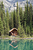 Cabin On Lakeshore Reflecting On Mountain Lake With Mountain In Background; Feld British Columbia Kanada