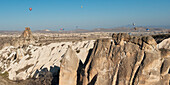 Heißluftballons füllen den blauen Himmel über einer zerklüfteten Landschaft; Nevsehir Türkei